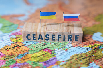Wooden blocks spelling Ceasefire with Ukrainian and Russian flags on a EUROPE map, symbolizing...