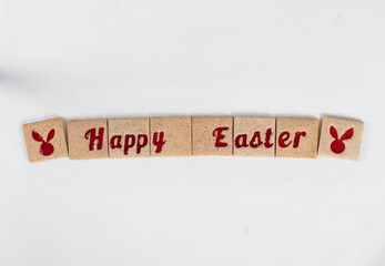 Happy Easter. Little Square cookies with red marmalade filling in the shape of Happy Easter words, in the shape of rabbit ears. White background. Top view