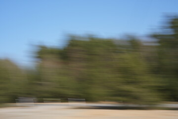 abstract blur of green foliage and blue sky creating dynamic motion effect in a natural outdoor...