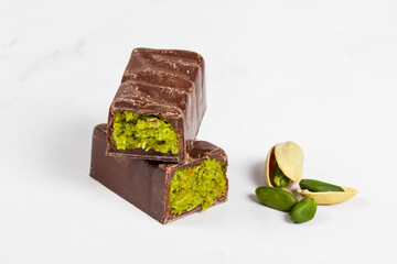 Dubai chocolate. Chocolate candy bar with crispy kataifi dough filling and emerald pistachio paste. White background. Close up