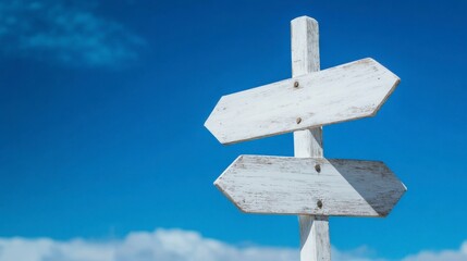 White, blank wooden signpost with arrows pointing in different directions against a blue sky background, with copy space for text