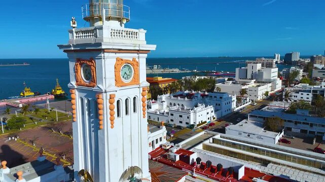 Veracruz, Veracruz, Mexico. February 24, 2025: Detail of the Venustiano Carranza Lighthouse Clock, a historic 1902 neoclassical building on the Gran Plaza del Malecon. Some cargo ships are in the port