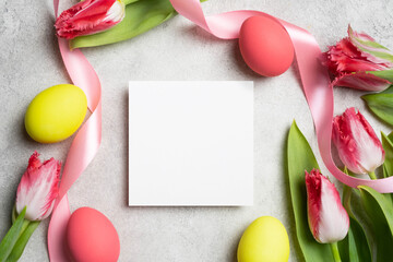 Square Easter card mockup with eggs, tulips flowers and blank card on grey background, top view with copy space