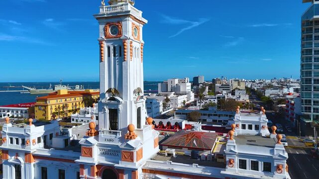 Veracruz, Veracruz, Mexico. February 24, 2025: Detail of the Venustiano Carranza Lighthouse Clock, a historic 1902 neoclassical building on the Gran Plaza del Malecon. Some cargo ships are in the port