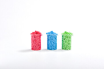 Blue, green and red masterbatch granules in measuring cup isolated on white background, color...