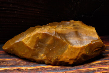 A flint spear tip with beautiful retouching on a wooden background, an ancient artifact of the...