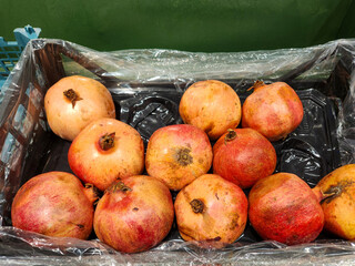 Pomegranates in crate, crate full of pomegranates in various shades of red and orange. Fresh produce.