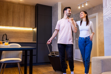 Young couple comes into the apartment for their vacation. They carry the baggage with them.