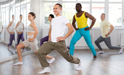 Obraz premium Group of multicultural men and women doing warm-ups before dance class in studio