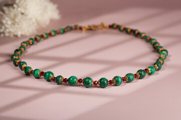 Malachite necklace photographed on a pink background