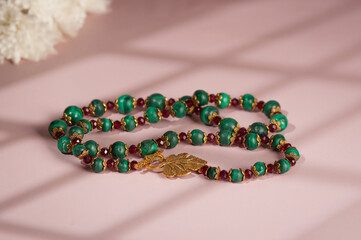Malachite necklace photographed on a pink background
