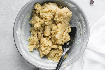 Overhead view of chocolate chip cookie dough, top view of homemade chocolate chip cookie dough in a bowl on a white background, process of making chocolate chip cookies