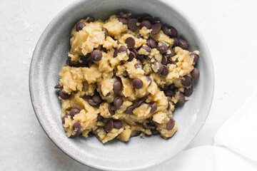 Overhead view of chocolate chip cookie dough, top view of homemade chocolate chip cookie dough in a bowl on a white background, process of making chocolate chip cookies
