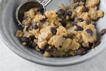 Overhead view of scooped chocolate chip cookie dough, top view of homemade chocolate chip cookie dough in a bowl on a white background, process of making chocolate chip cookies