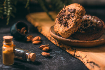 Delicious chocolate and nut cookies on a rustic plate, surrounded by almonds and walnuts. Warm lighting and earthy tones create a cozy and inviting homemade bakery atmosphere.