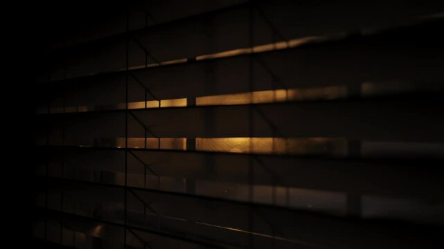 Looking at golden sunset through window closed by blinds. Close up footage