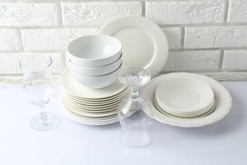 Different clean dishware on white table near brick wall