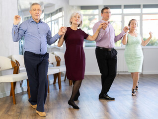 Group of men and women dancing traditional folk dance in studio