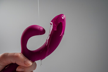 Lube pouring on pink dildo on white background. 