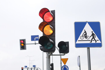 Red and yellow traffic lights at an intersection on a cloudy day. Road safety and transportation control signals. Urban street scene showing a change of lights guiding vehicles and pedestrians.
