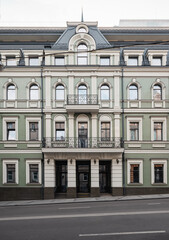 Fototapeta premium Facade of a classic style building with beige window surrounds. Entrance into a green building in old town.