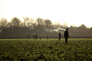 Skilled hunters participate in exciting wild hare shooting event in a lush green field at twilight
