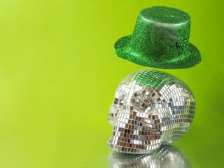 Green Irish hat with glitter floating over a party scull with mirrors. The scull is on a reflective surface, Yellow green background.
