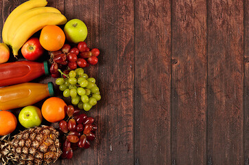 Healthy vegan products for a healthy lifestyle. Grapes, oranges, pineapple, apples, bananas, nuts and natural juice on a wooden background, detox diet and weight loss concept, store advertisement