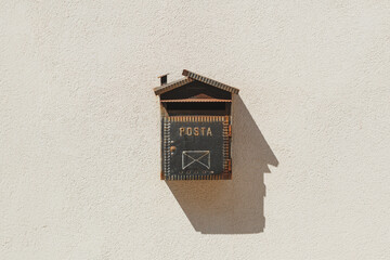 A classic mailbox set on a wall, adorned with a shadow cast beautifully beside it