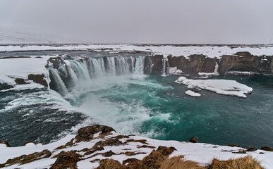 Powerful waterfall cascading over rocks in snowy landscape in Iceland  © Eclipsnet