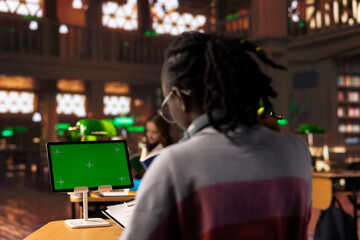 African american pupil uses green screen extracting citations from specialty books and other reliable academic sources, research tools within the university campus library. Self learning.