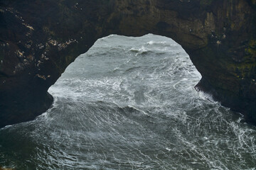 Powerful waves crashing on the rocks of a scenic coastline with a natural arch