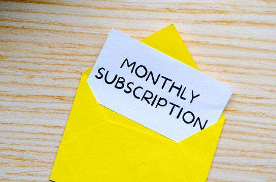 Monthly Subscription text on white notepad inside a yellow envelope. Online marketing concept