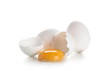 Whole and cracked chicken eggs on white background