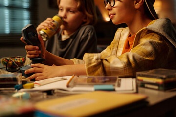 Two children engrossed in playing a vintage video game console surrounded by various nostalgic objects on desk creating a sense of shared fun and nostalgia