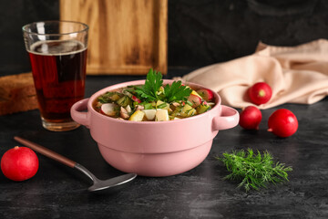 Bowl with tasty okroshka, fresh radish and glass of kvass on dark background