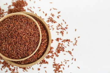 Wooden bowls with raw brown rice on white background