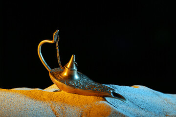 Lamp of Aladdin with color sand on dark background