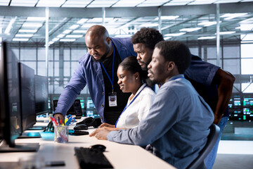 Group of technicians doing brainstorming, reconfiguring server farm to optimize it for data...