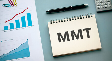 There is notebook with the word MMT. It is an abbreviation for Modern Monetary Theory as...