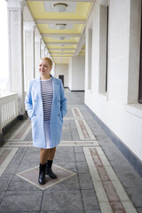 Obraz premium A woman in a coat walking in the park. Stylishly dressed blonde