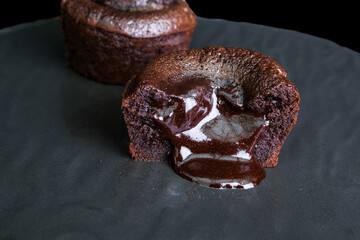 Chocolate lava cakes oozing with melted chocolate filling on a dark plate