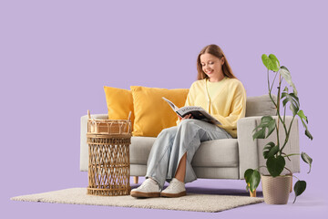 Young woman reading magazine on grey sofa against purple background