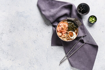 Bowl of ramen noodle soup with shrimps and seaweed sheets on white background