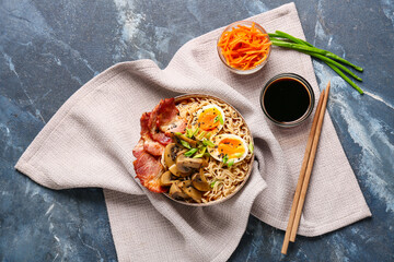 Bowl of ramen noodle soup with bacon and mushrooms on blue background