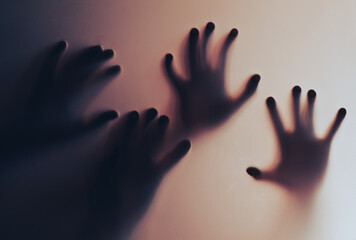 Silhouetted Hands Pressing Against Blurred Glass in a Dramatic Setting