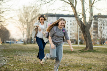 Obraz premium A woman joyfully chases a girl through the park, celebrating their bond with shared laughter and playfulness.