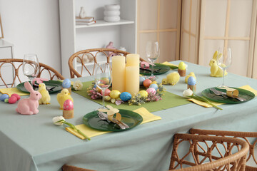 Beautiful table setting with candles, decorative chickens and Easter eggs in dining room