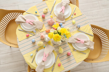 Beautiful table setting with flowers and Easter eggs in dining room