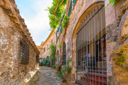 A narrow cobblestone alley inside the fortified walls of the Murallas de Tossa de Mar, Spain, a 12th century castle overlooking the Mediterranean Sea.